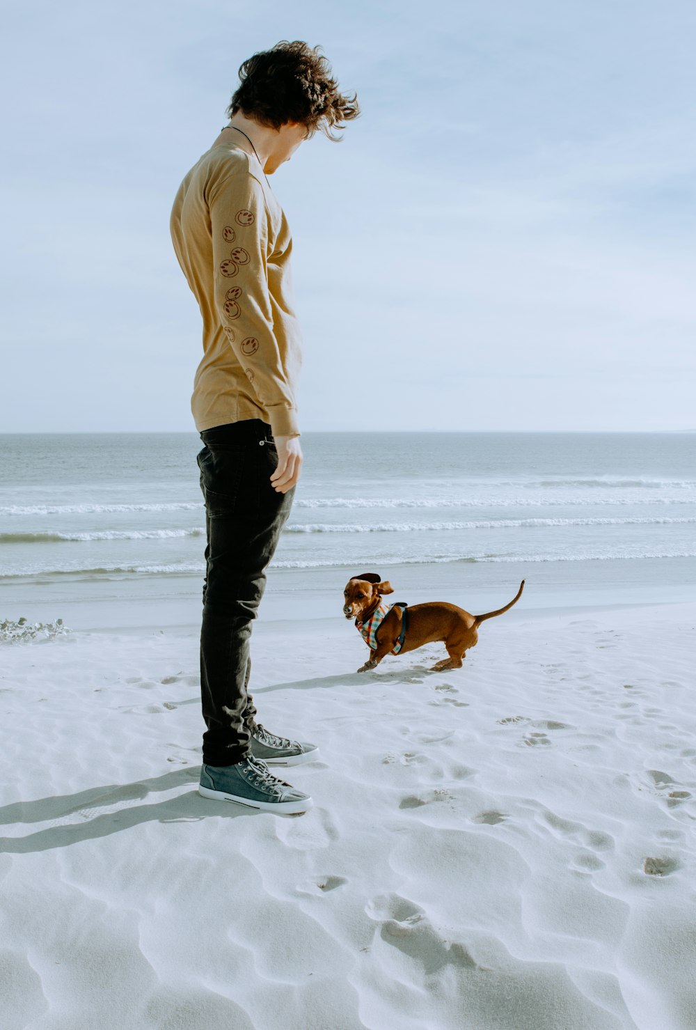 woman in beige jacket and black pants standing on snow covered ground beside brown short coated