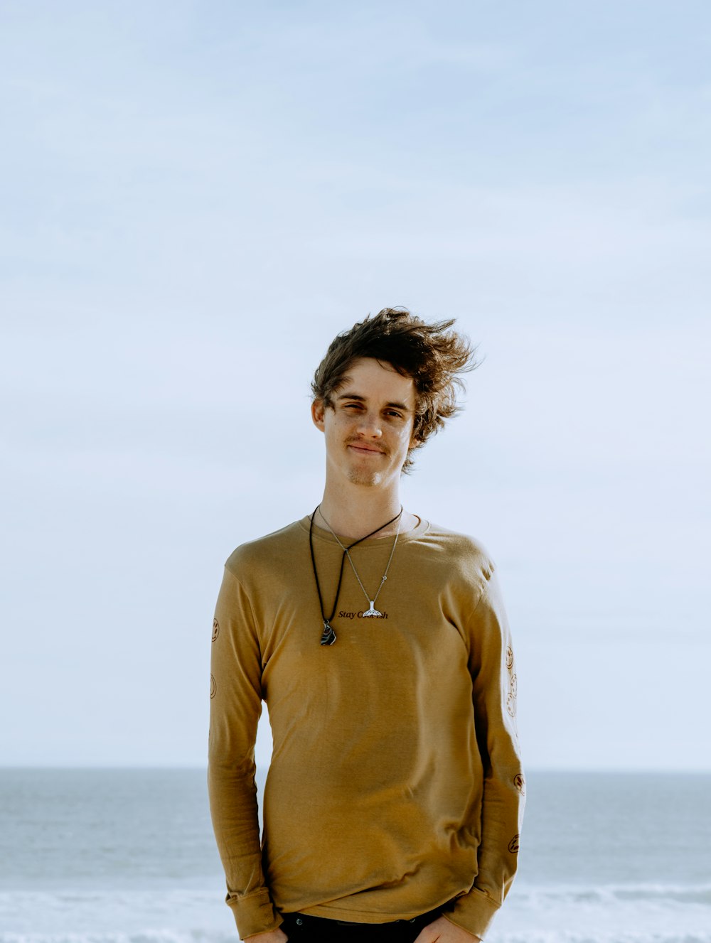 man in brown turtleneck sweater standing near sea during daytime