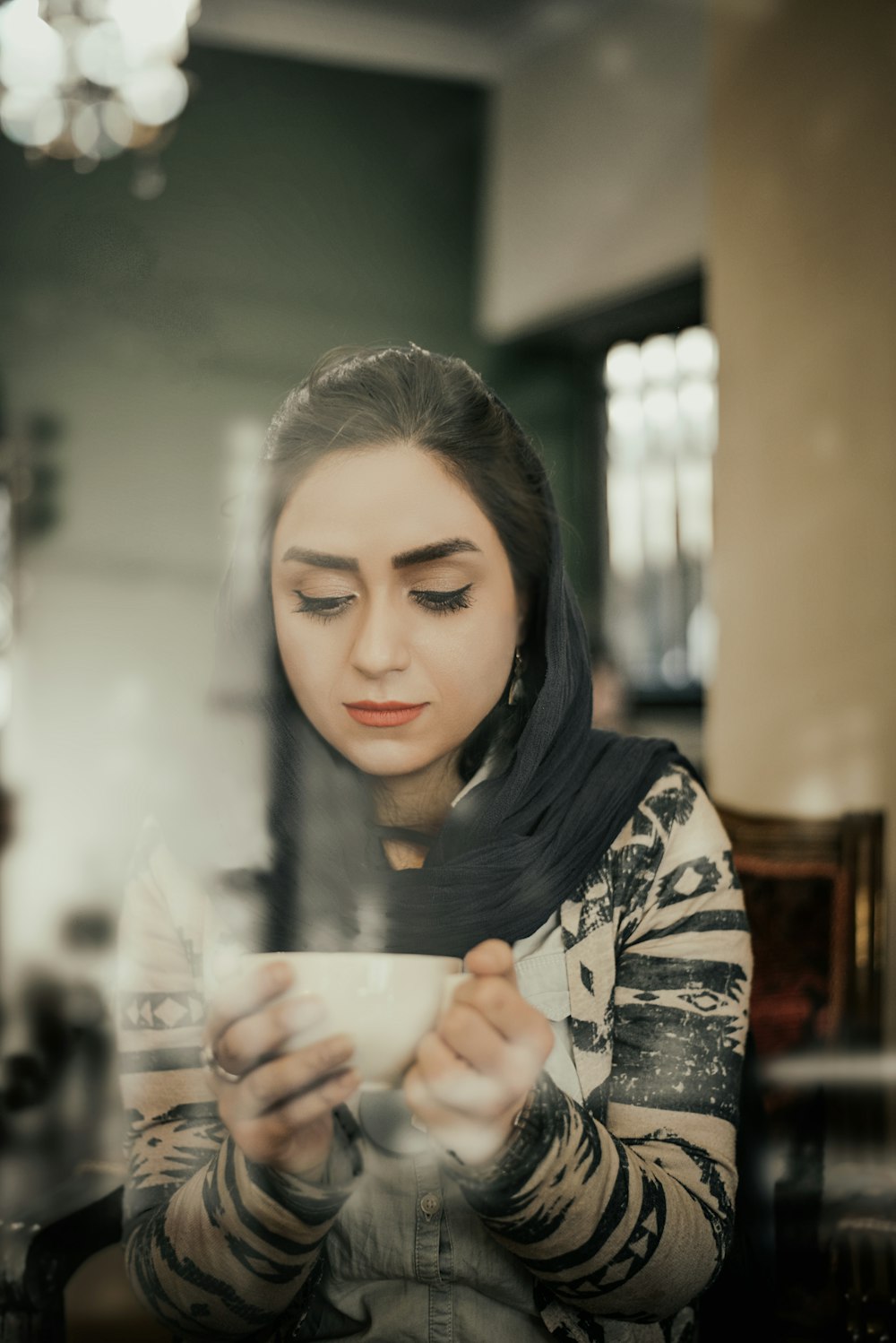 woman in black and white floral long sleeve shirt holding white ceramic mug