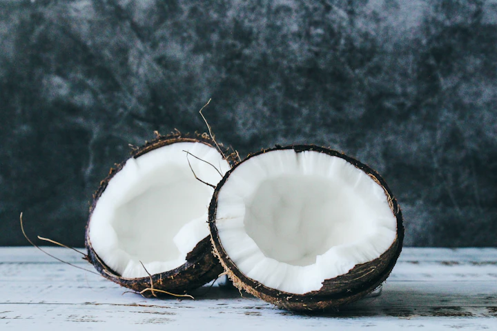 A cracked coconut on a white wooden table