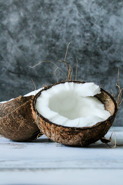 a close up of a coconut shell broken in half to show the white coconut meat