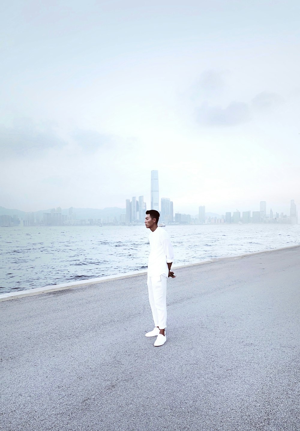 woman in white long sleeve shirt and white pants standing on gray concrete road during daytime