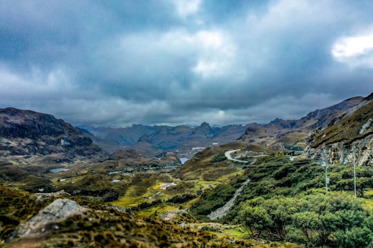 green grass field and mountains under white clouds in Cuenca Ecuador