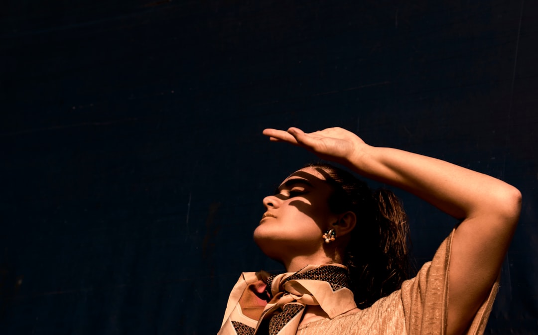 woman in brown and white plaid shirt raising her hands