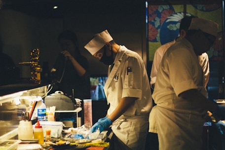 Sterile kitchen environment with staff wearing gloves and masks.