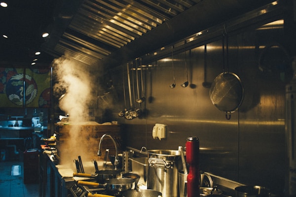 Pots on a commercial kitchen stove preparing barbecue sides