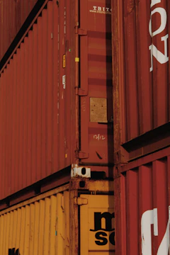 Close-up of hands shaking over a contract with shipping containers in the background.
