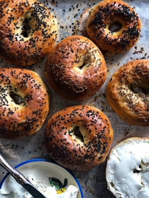 A tray of assorted bagels fresh out of the oven, showcasing different flavors and toppings.