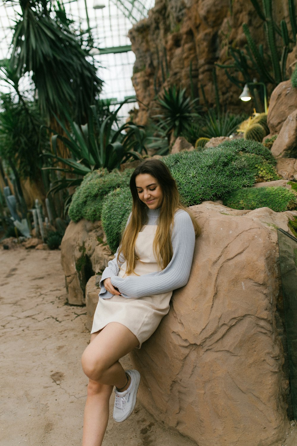 woman in white dress sitting on brown rock