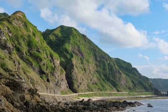 green mountain under white clouds during daytime in Batanes Philippines