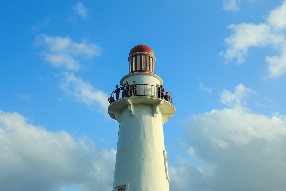 white and red concrete lighthouse under blue sky during daytime