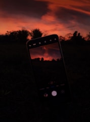 A smartphone camera capturing a vibrant sunset over a city skyline.