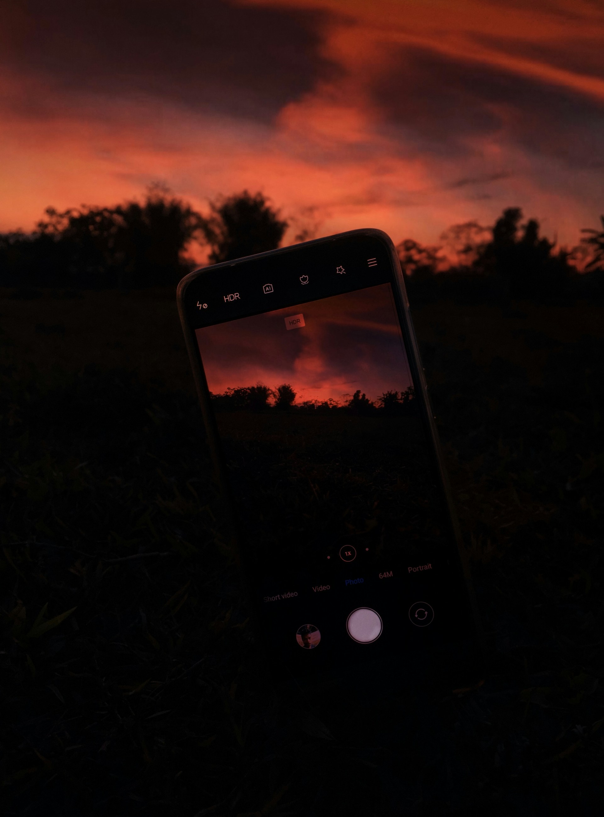 A close-up shot of a smartphone capturing a vibrant sunset over a city skyline.