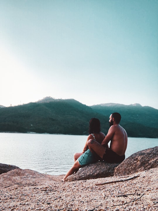 woman in blue bikini sitting on rock near body of water during daytime in Gerês Portugal