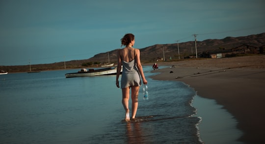 woman in white tank top and gray shorts standing on beach shore during daytime in Cabo de La Vela Colombia