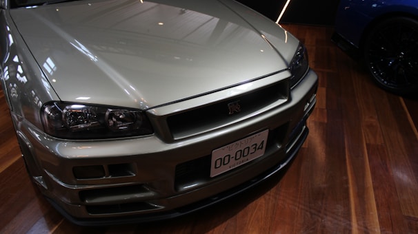 Finished car with flawless metallic silver paint reflecting showroom lights, showcasing premium coating quality.