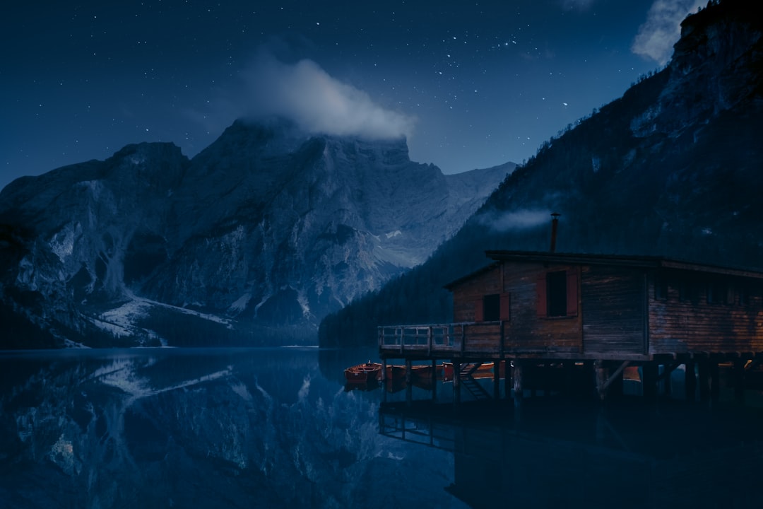 brown wooden house on lake near mountain