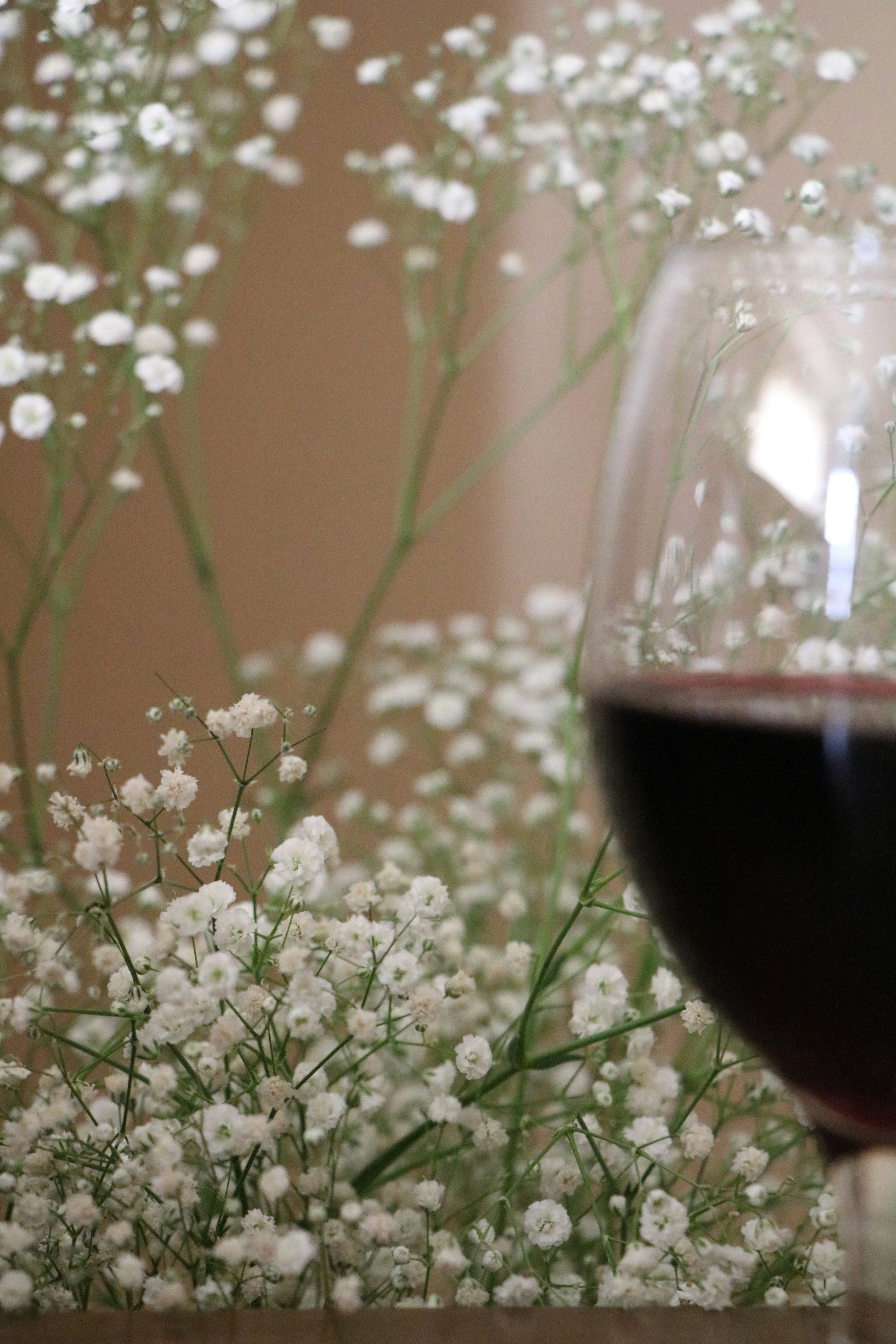 flores brancas ao lado de copo de vinho transparente
