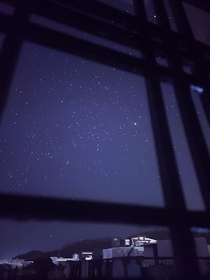 A serene night sky filled with stars viewed through a bedroom window.