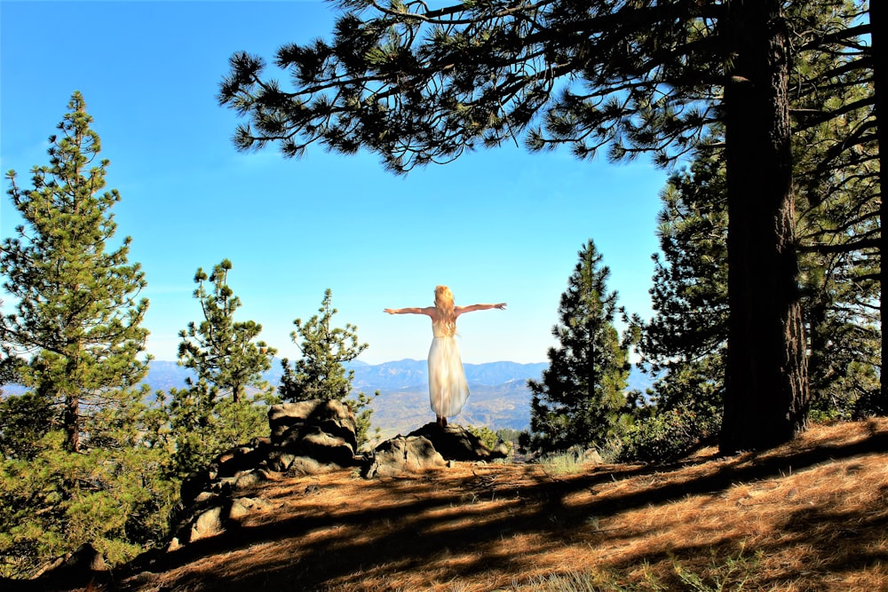 woman in white long sleeve shirt sitting on brown tree log during daytime