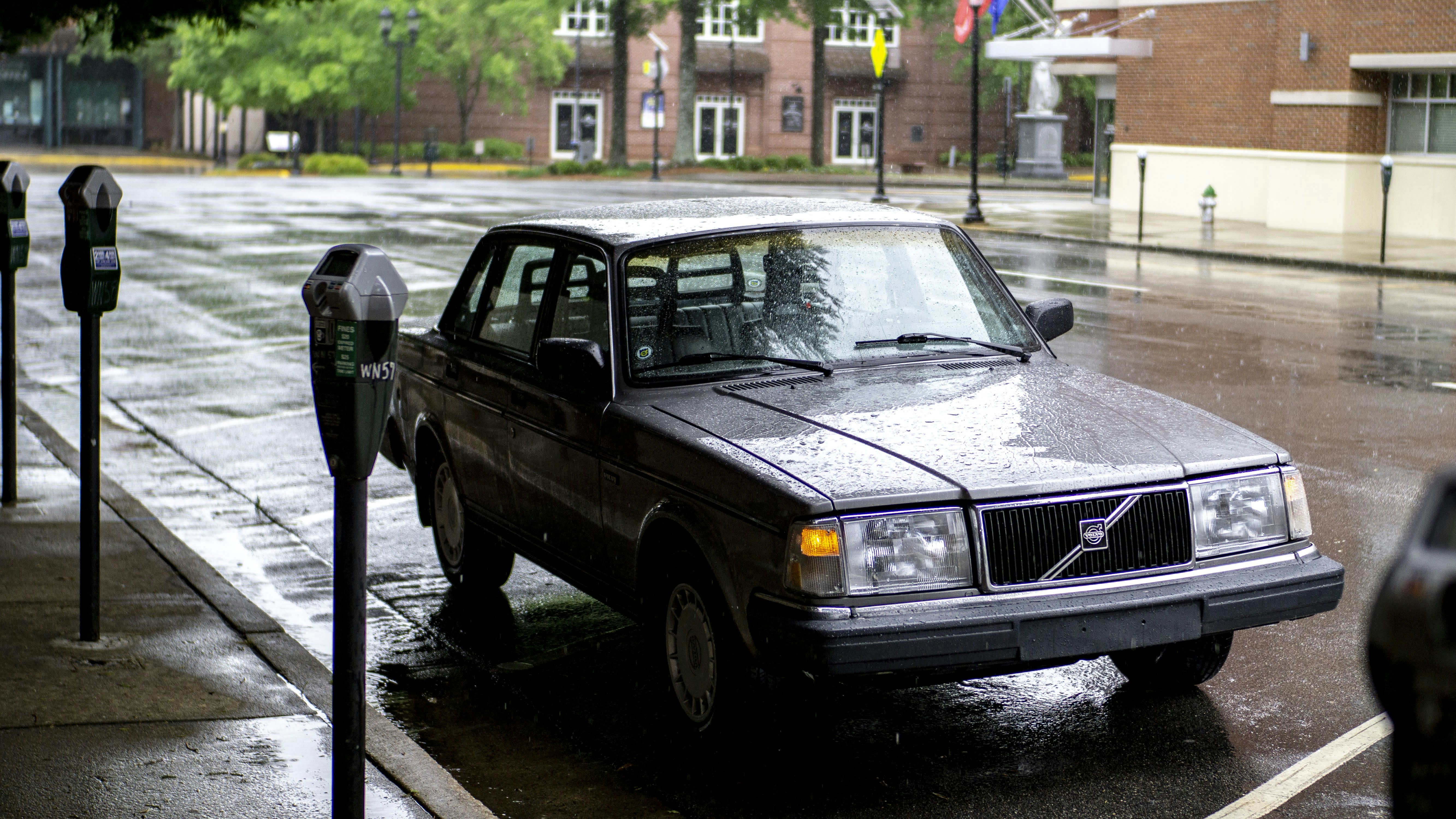 black sedan parked on sidewalk during daytime