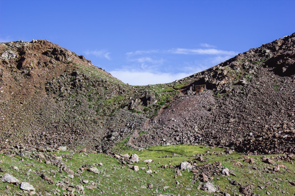 green grass field on mountain under blue sky during daytime