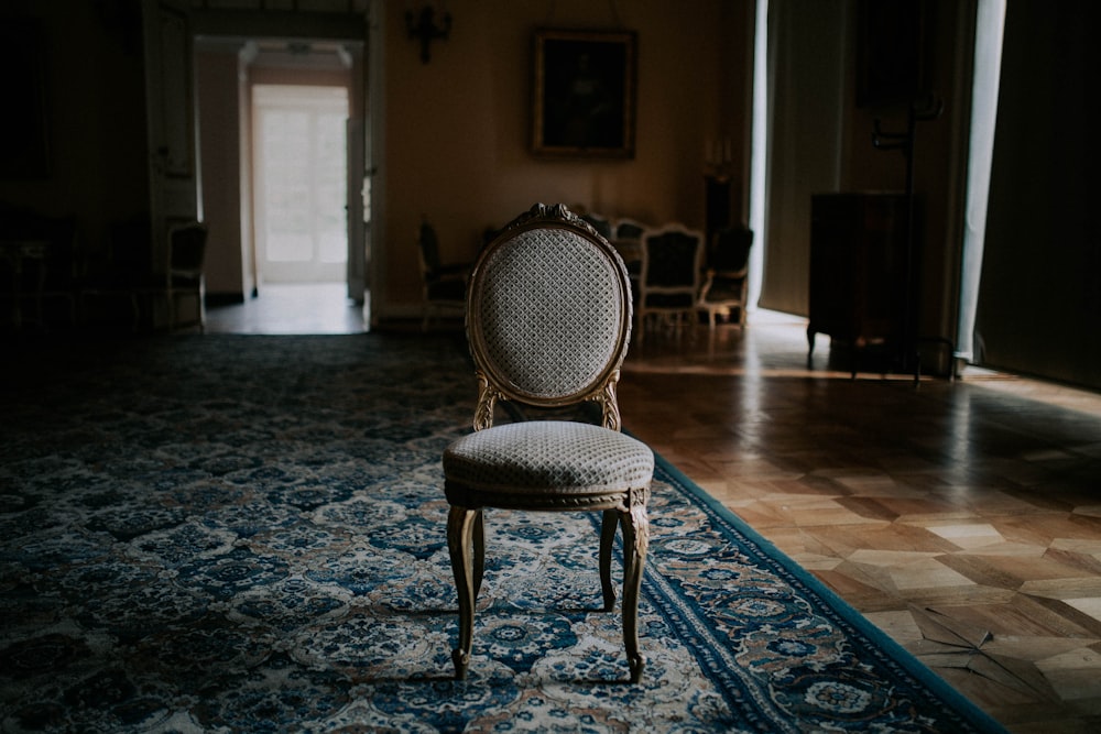 Silla de madera marrón sobre alfombra floral azul y blanca