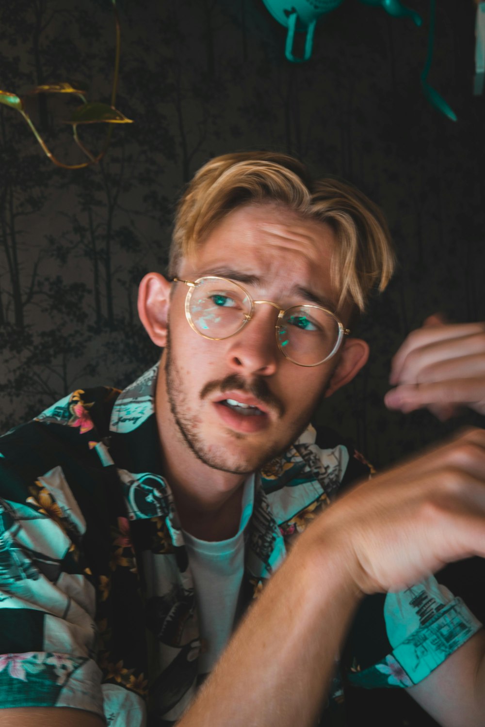 man in black green and white floral button up shirt wearing eyeglasses