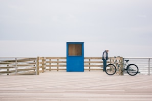 man in black shirt and blue denim jeans riding bicycle on white sand during daytime