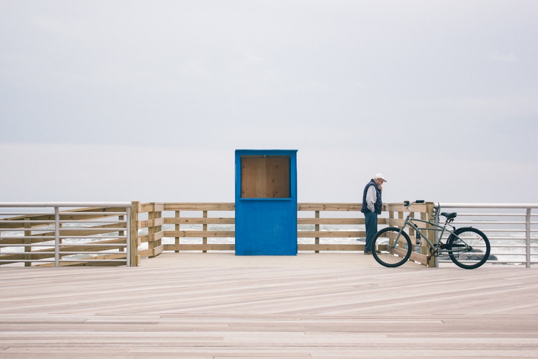 man in black shirt and blue denim jeans riding bicycle on white sand during daytime