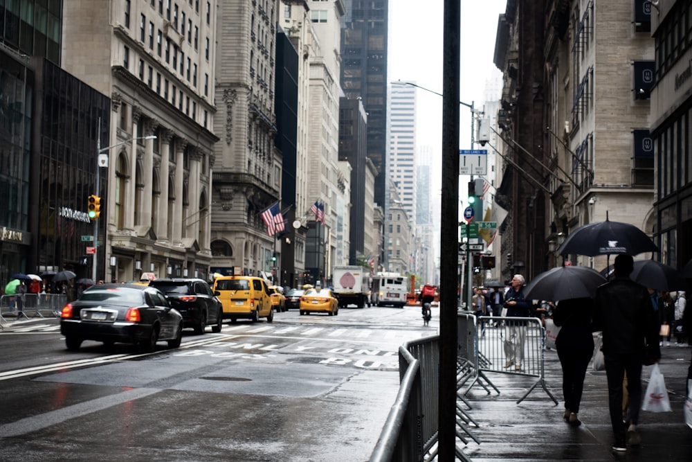 cars on road between high rise buildings during daytime