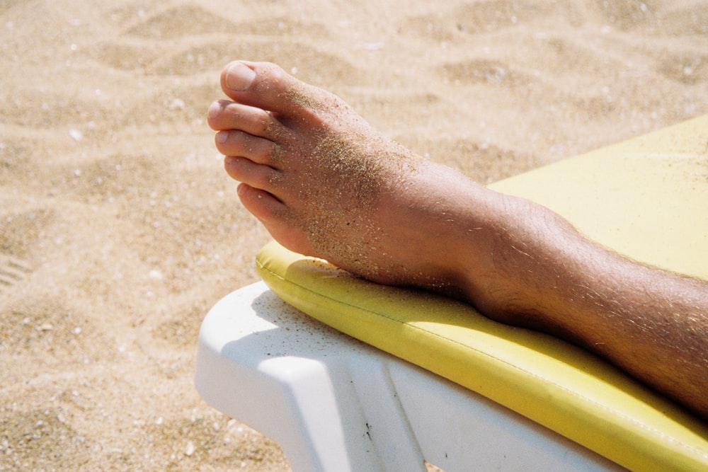 persons feet on yellow and white towel