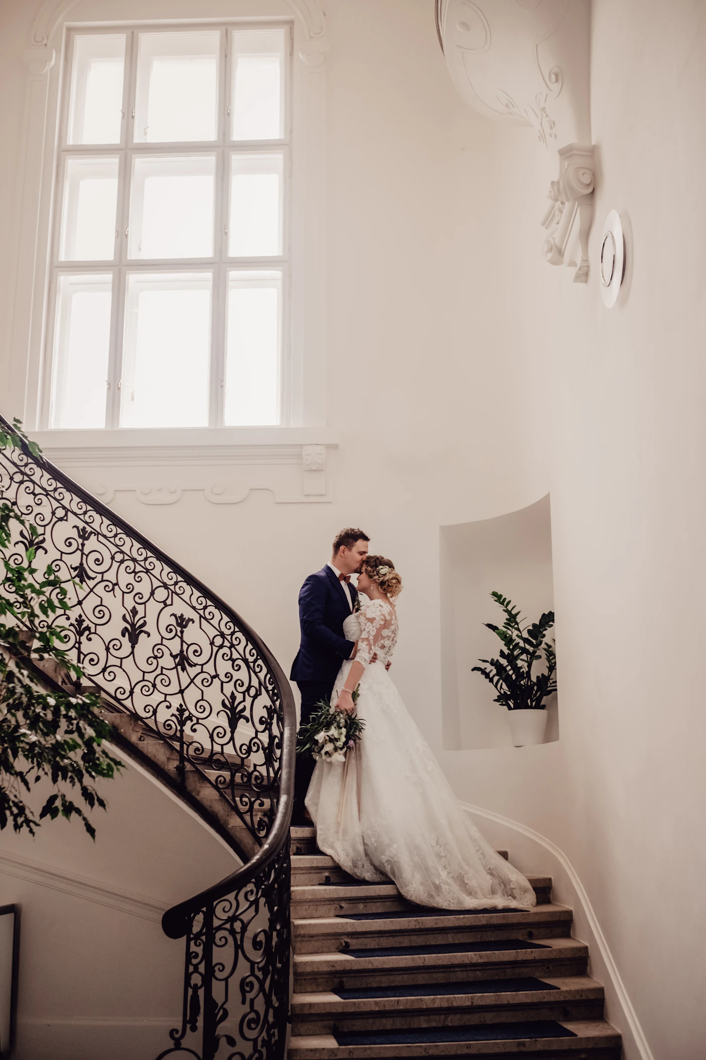 Bride and groom on a grand wrought-iron staircase at a chateau-style wedding venue