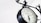 A vintage-style clock with Roman numerals, mounted on an ornate black metal bracket. The clock face reads 'Paddington Station London 1854' and is set against a clean, white background, giving a classic and elegant appearance.