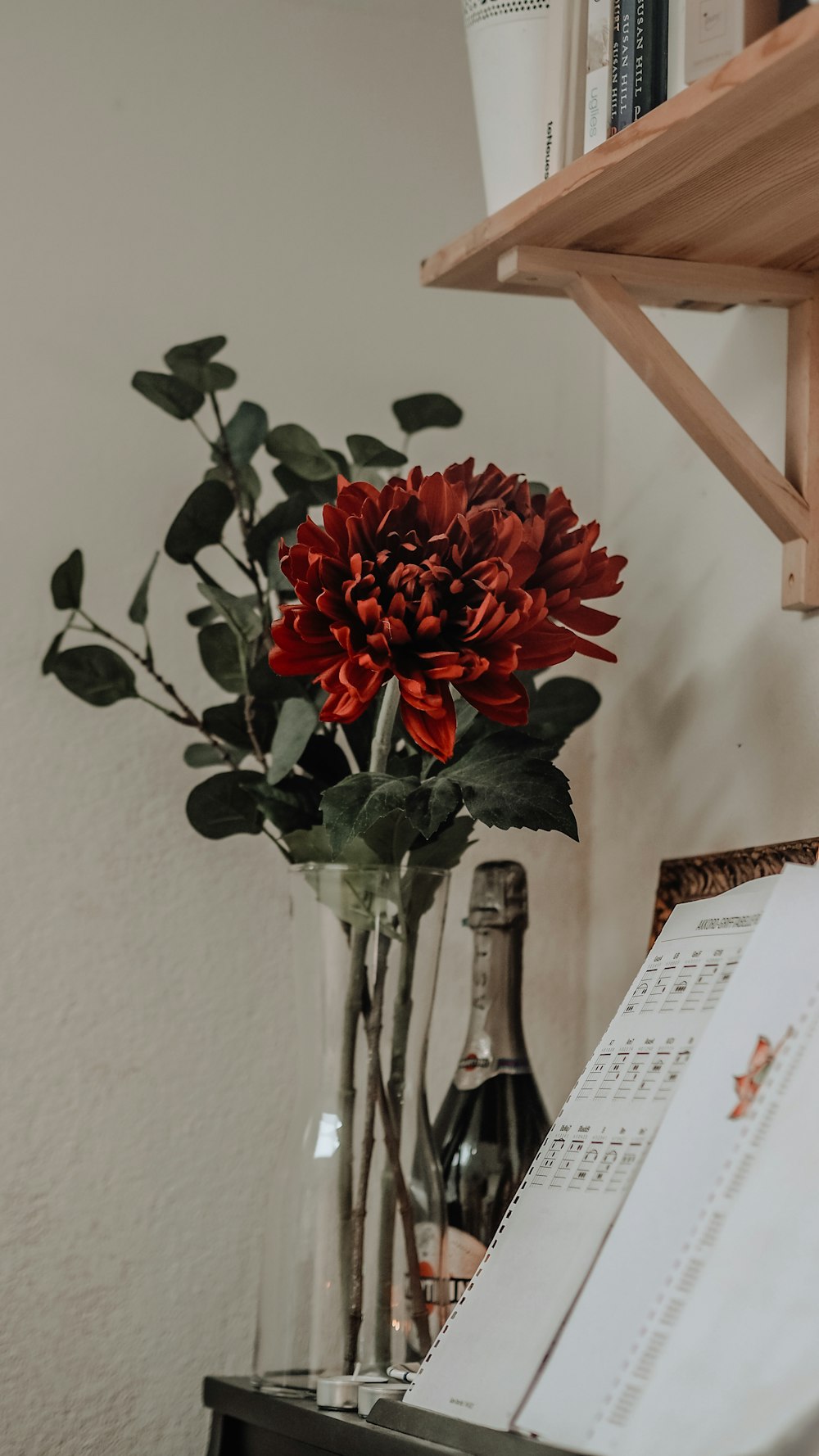 a vase filled with red flowers next to a piano