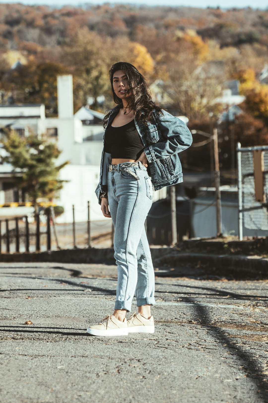 woman in black long sleeve shirt and blue denim jeans standing on gray concrete road during