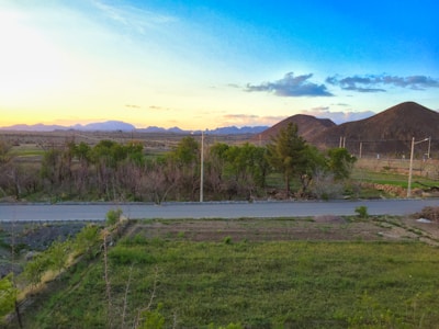 A peaceful rural landscape with a dirt road and distant mountains.