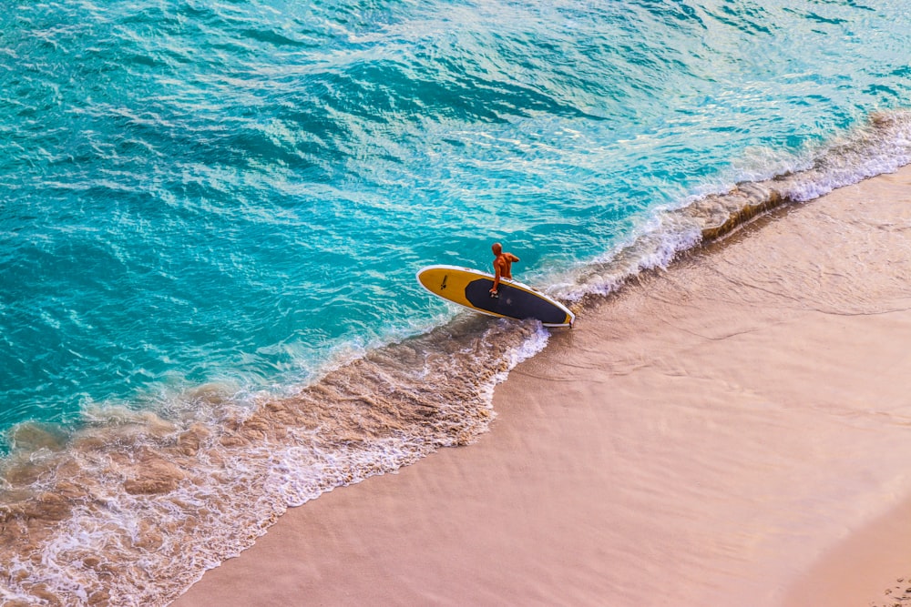 man in yellow surfing board on sea waves during daytime