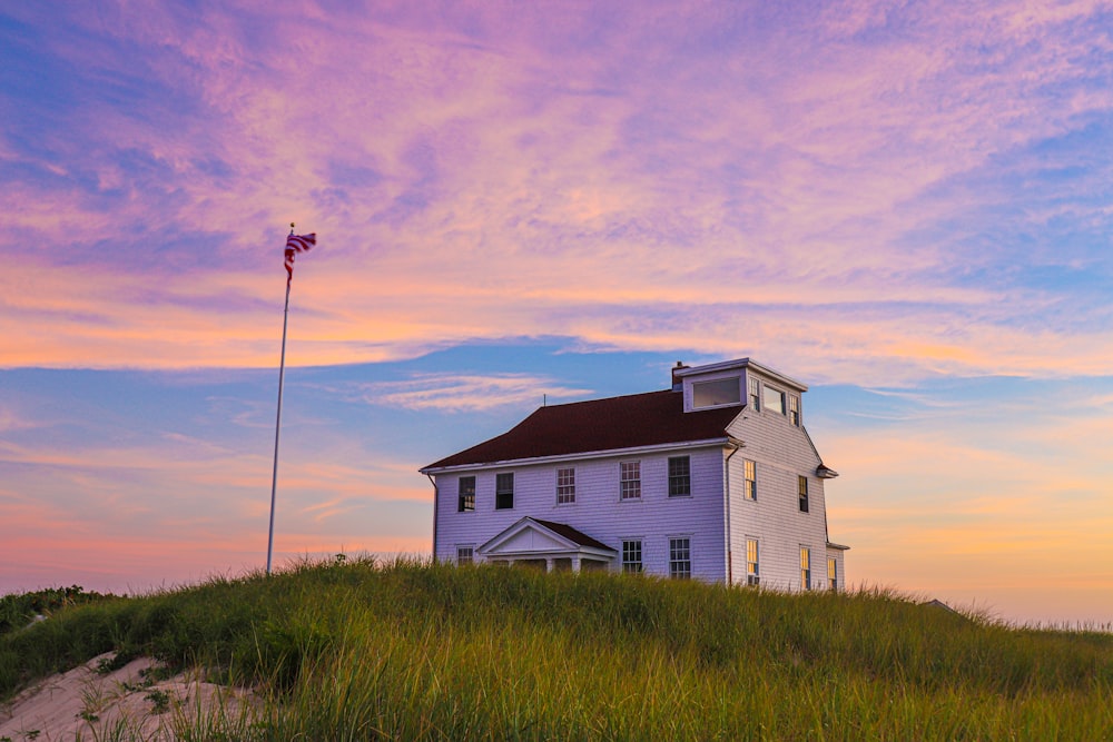 white and brown house near green grass field under white clouds and blue sky during daytime