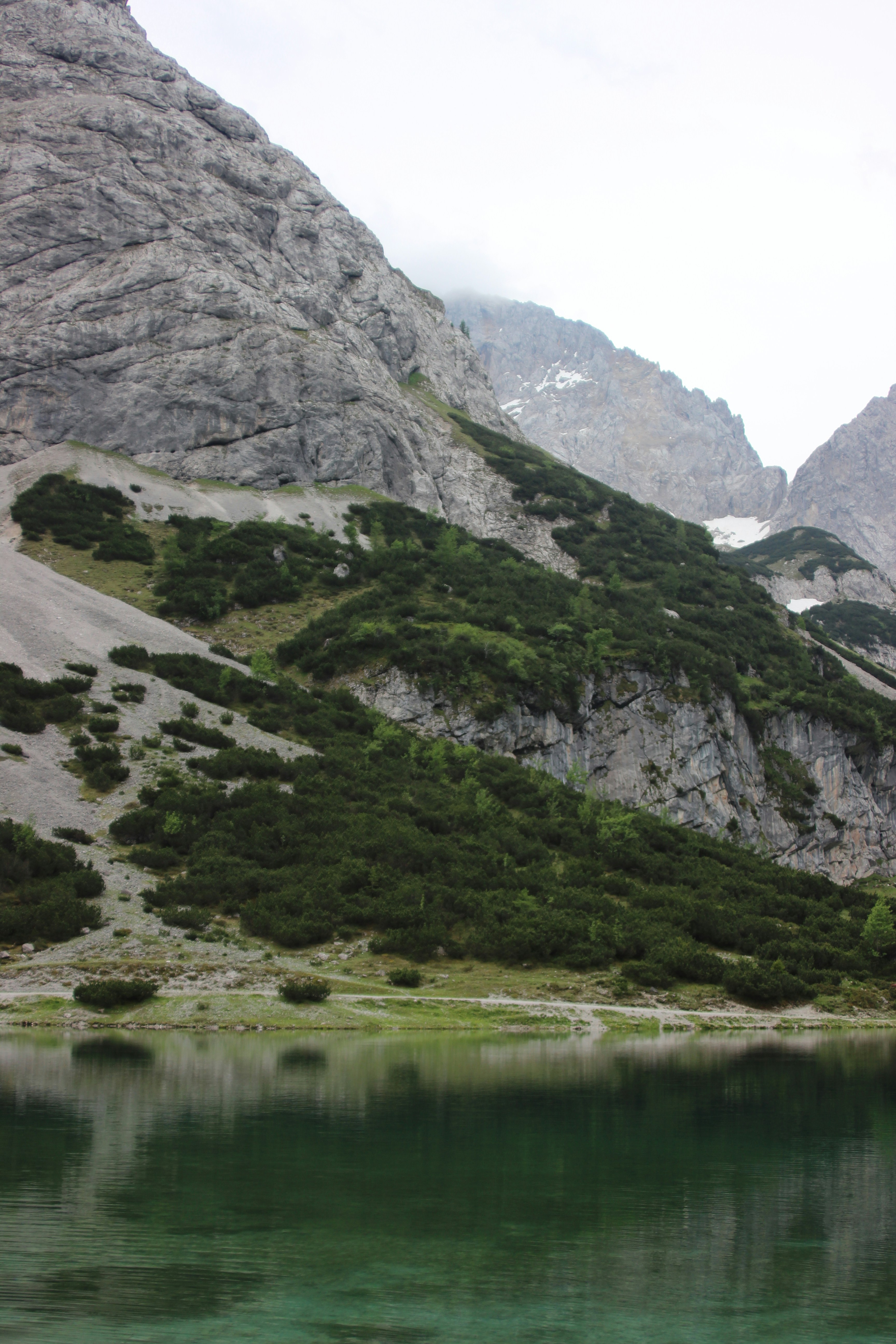 Gunung hijau dan abu-abu di samping danau pada siang hari