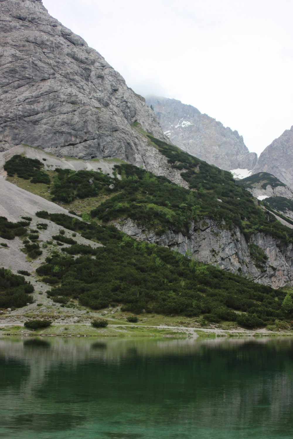 green and gray mountain beside lake during daytime