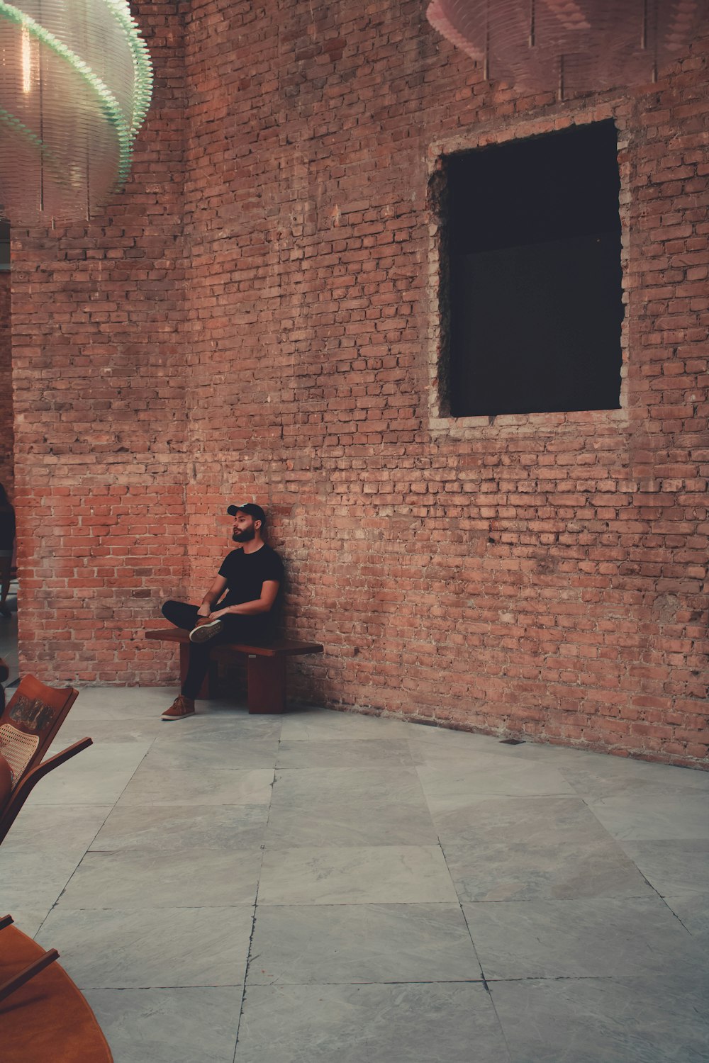 man in black shirt playing guitar sitting on brown wooden chair