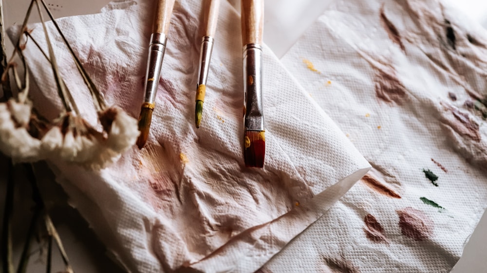 brown and silver makeup brush on white textile