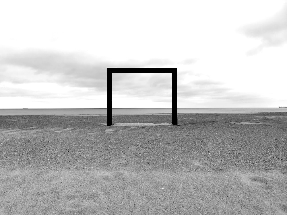 grayscale photo of wooden frame on sand