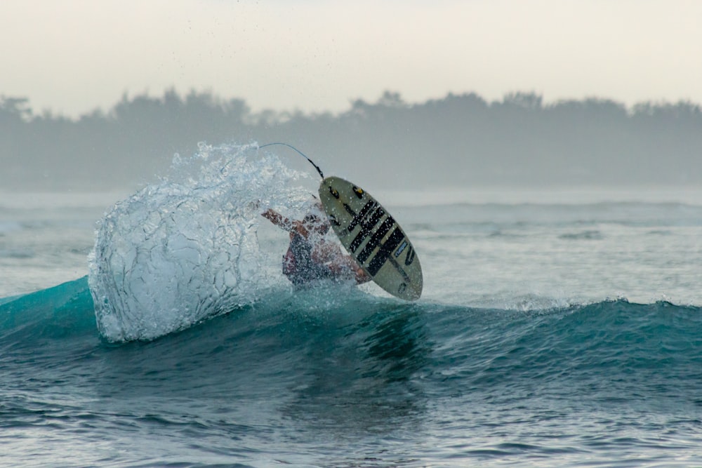 man in black and white striped shirt surfing on sea waves during daytime