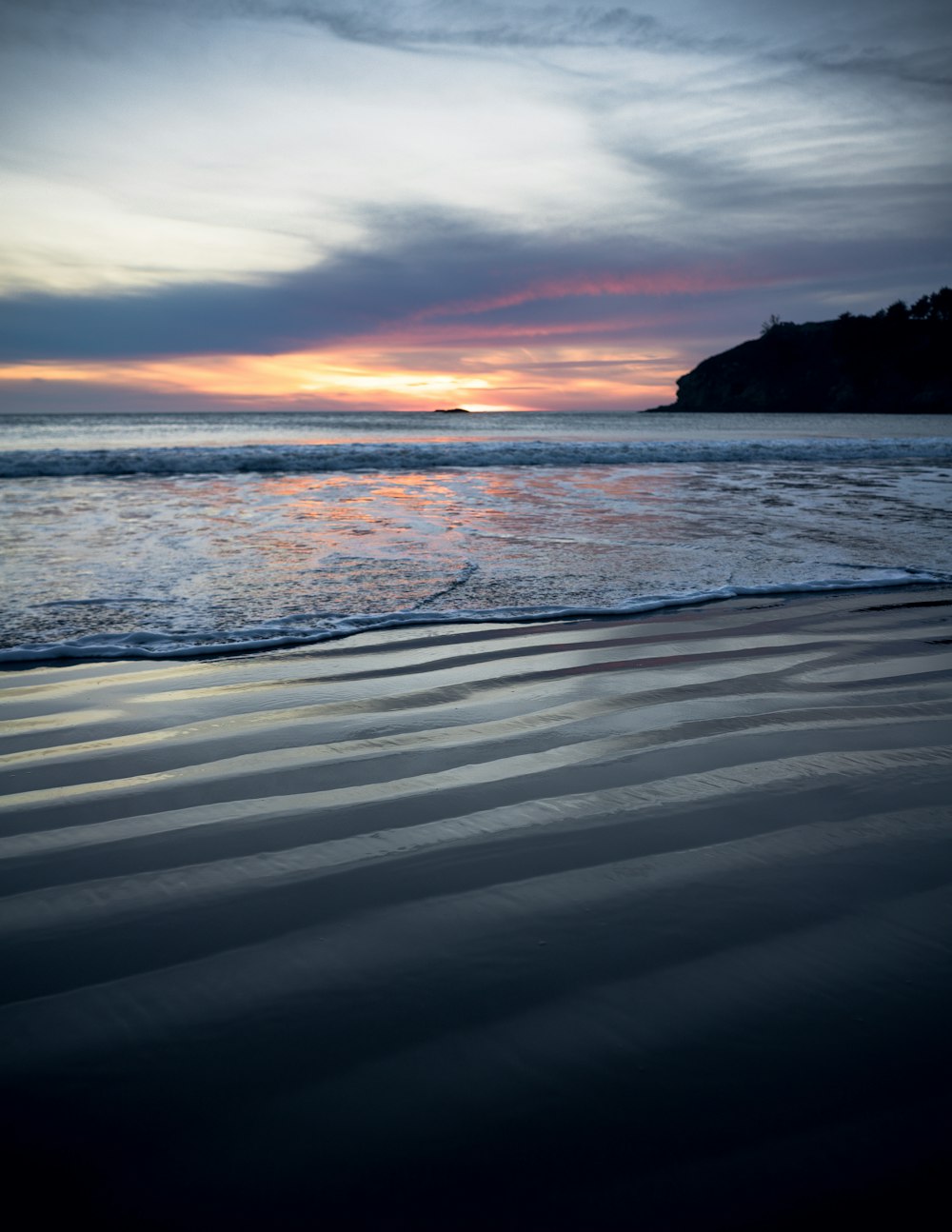 ocean waves crashing on shore during sunset