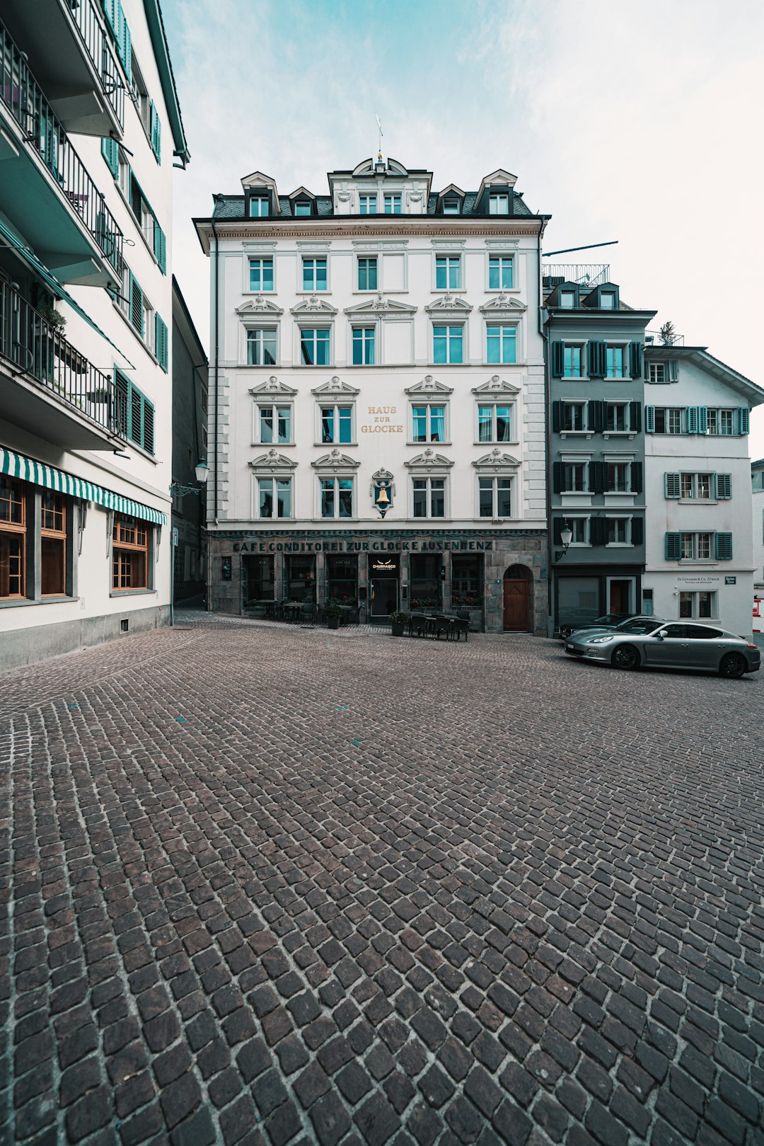 white car parked beside brown concrete building during daytime