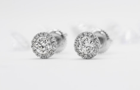 Elegant diamond earrings sparkling under warm lighting on a minimalist white background.