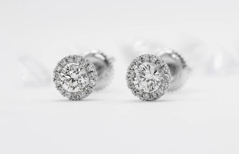 Pair of round halo diamond stud earrings on a soft white background