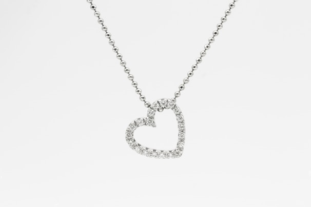 Close-up of a sparkling diamond heart pendant glowing softly against a dark velvet background